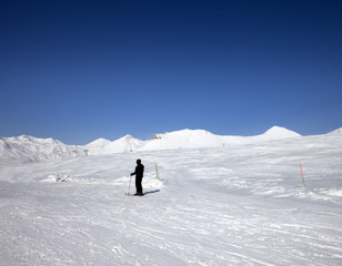 Skier on ski slope at sun day