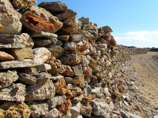 Rough wall stone with blue sky and a road