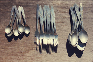 Aluminium spoons, forks. Old aluminium spoons and forks on a wooden surface. Old tableware