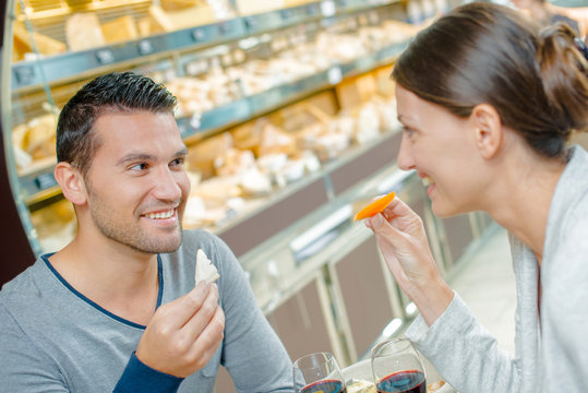Couple eating meal, holding cheeses