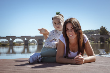 Madre e hija acostadas en el embarcadero. Una niña y su mama disfrutando del verano junto al rio....