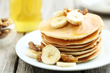 Tasty pancakes with banana and walnut on grey wooden background
