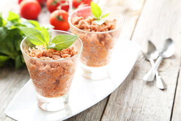 Glass with granita from fresh tomatoes on grey wooden background