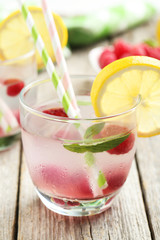 Raspberries and juice in glass on grey wooden background
