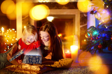Mother and little daughter opening a magical Christmas gift