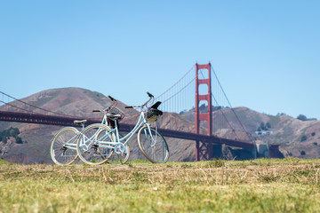 Two bicycles parked on grass in front of Golden Gate Bridge