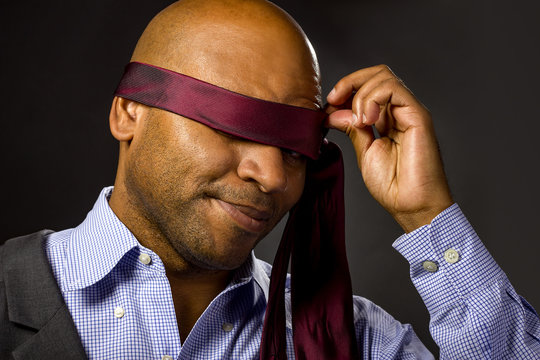 Black businessman blindfolded to represent corporate uncertainty