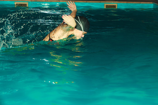 Woman athlete swimming butterfly stroke in pool.