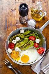 Breakfast in a frying pan. fried eggs with salad. fried green pe