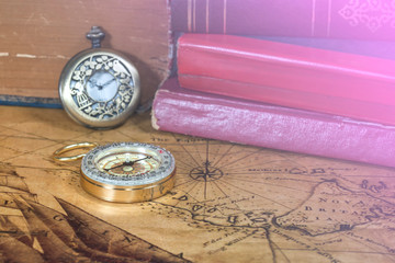 Vintage pocket watch and compass on old map background
