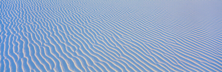 These are white sand dunes in morning light. There are line patterns in the sand from the wind.