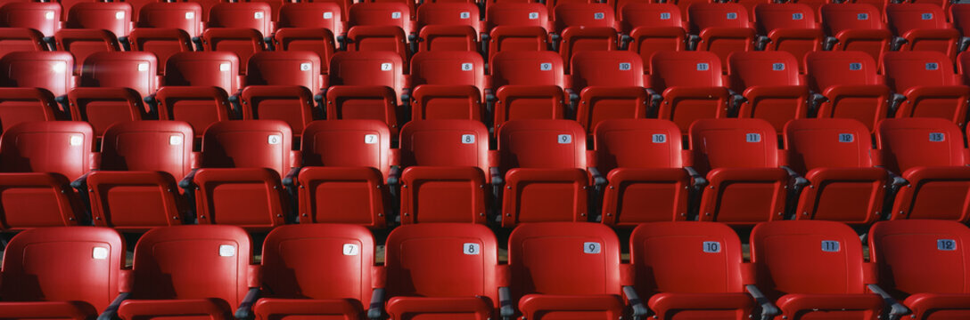 These are bright red outdoor stadium seats with seats that fold up. They are located at a baseball stadium.