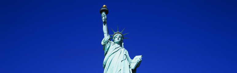 This is the top half of the Statue of Liberty against a blue sky in horizontal format. © spiritofamerica