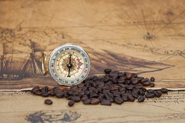 Vintage compass and bean lies on an ancient map