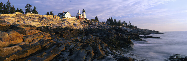 This is the Pemaquid Point Lighthouse at sunrise. It was built in 1827. Below the lighthouse are the rocks that have been smoothed by the ocean wearing them down. The ocean lightly meets the bottom of the rocks at low tide.