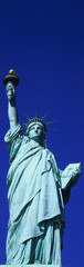 This is a vertical shot of the Statue of Liberty against a blue sky.