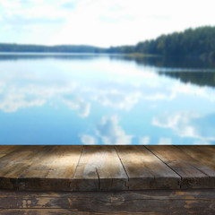 vintage wooden board table in front of dreamy and abstract forest lake landscape 