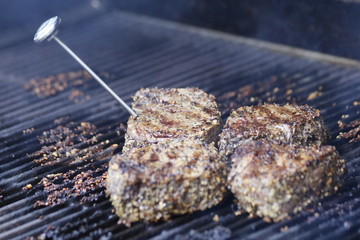Food: Steak on the grill during a bbq with a thermometer to check the temperature. 