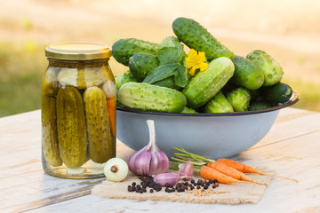 Cucumbers in metal bowl, vegetables and spices for pickling and jar pickled cucumbers