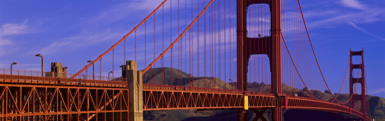 This is a close up view of the Golden Gate Bridge with a view of Marin County in the background. It is a spring morning.