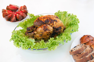 A whole roasted chicken with green salad, bread and tomatos