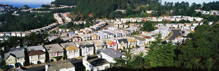 Fototapeta na wymiar These are houses lined up in rows. They form a pattern and show urban congestion in housing. This is the view from Twin Peaks Mountain. There are green trees interspersed between the houses.