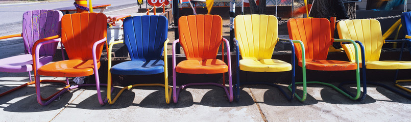 This is a close up of multi-colored metal lawn chairs. They are located outdoors on Route 66.
