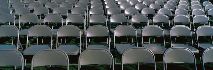 These are empty, grey folding chairs awaiting the crowd to attend the U.S. Naval Academy, Graduation Ceremony. They are neatly set up in rows side by side.