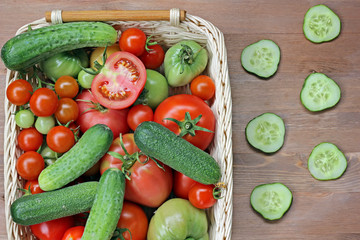 Fresh cucumbers, red and green tomatoes in a basket