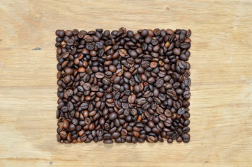 Square from coffee grains on a wooden surface.