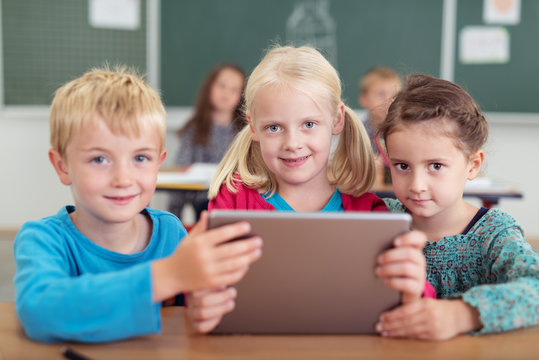 drei kinder in der grundschule mit tablet-pc