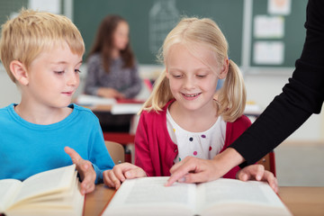 leherin zeigt den schulkindern etwas im buch