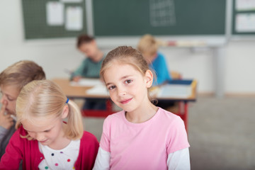 süßes mädchen in der grundschule schaut lächelnd in die kamera