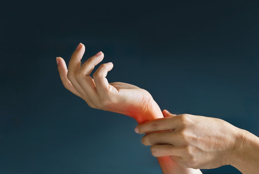 Acute pain in a woman wrist, colored in red on dark blue background