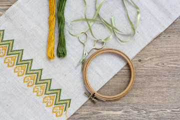 Ukrainian embroidery on the linen fabric and thread embroidery on a wooden table, selective focus