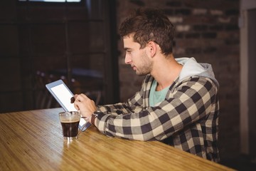 Hipster having coffee and using tablet computer