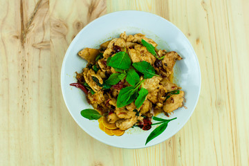 Spicy Thai basil chicken ready to eat on traditional plate with wooden spoon. Top View. (Shallow aperture intended for  the aesthetic quality of the blur.)