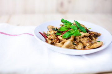 Spicy Thai basil chicken ready to eat on traditional plate. (Shallow aperture intended for  the aesthetic quality of the blur.)