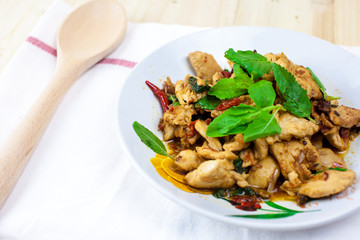 Spicy Thai basil chicken ready to eat on traditional plate. (Shallow aperture intended for  the aesthetic quality of the blur.)