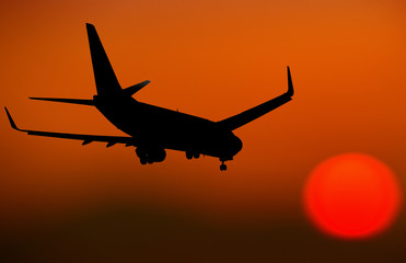 Fototapeta na wymiar Airplane Silhouette going towards the sun at dusk
