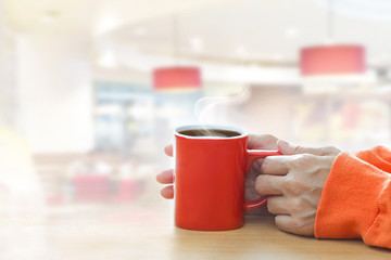 Red coffee cup with smoke in woman hands in coffee shop