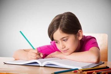 Composite image of cute pupil working at her desk