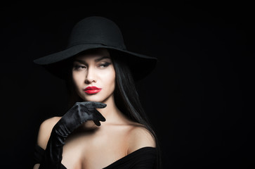 Fototapeta na wymiar Woman in big black hat, studio portrait, dark background