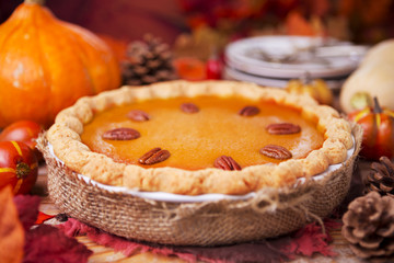 Homemade pumpkin pie on a rustic table with autumn decorations