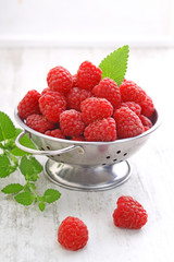 ripe raspberries with mint leaves on a white background