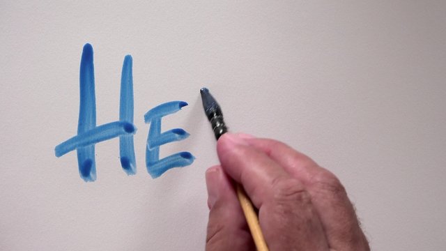 Human hand writing word "HELLO" with blue gouache