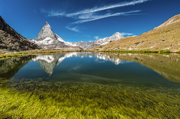 Matterhorn mountain behind a beautiful lake with grass