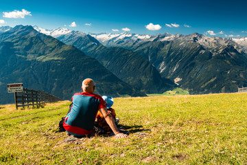 grandfather with kid sitting on grass with view to mountain peaks