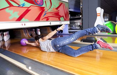 young woman sliding down a bowling alley