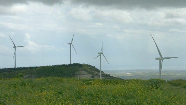 Wind turbine propellers spinning in wind, windmills in beautiful green field